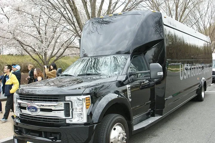 A tour bus parked beside a floodlit monument at night on a Washington DC tour for seniors