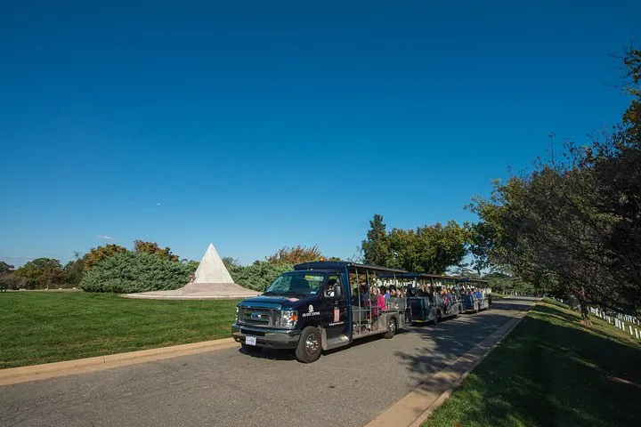 A cemetery trolley driving past rows of white headstones on a Washington DC tour for seniors at Arlington National Cemetery